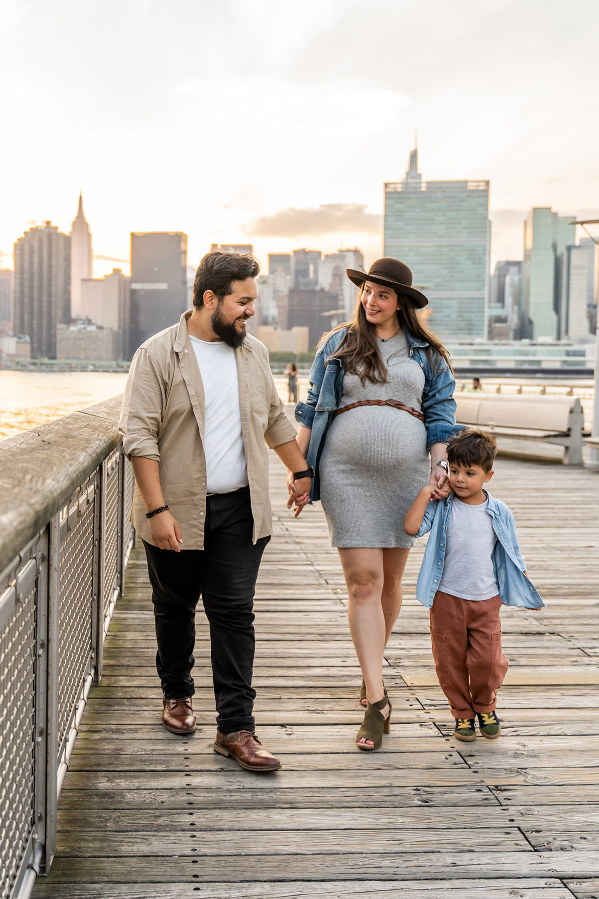 family with pregnant woman with hat on in queens with nyc skyline