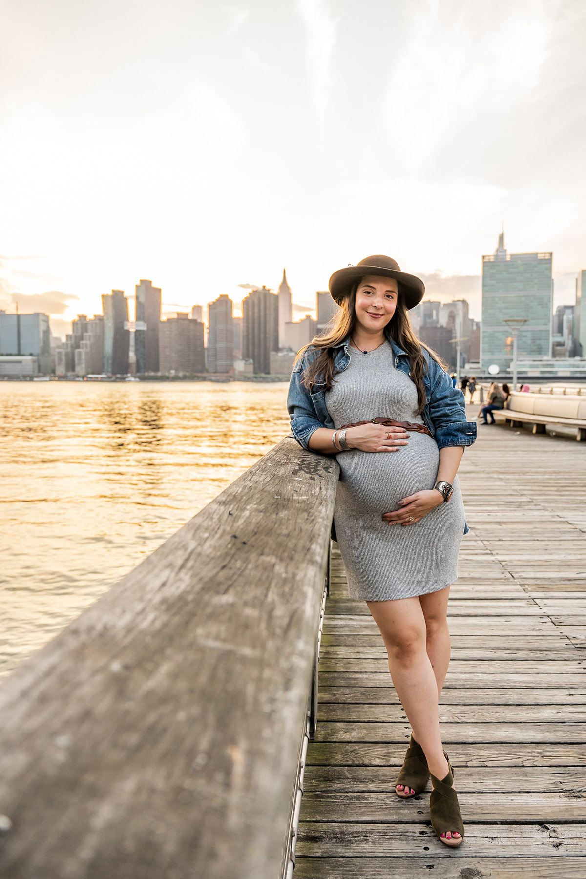 pregnant woman with hat on in queens with nyc skyline