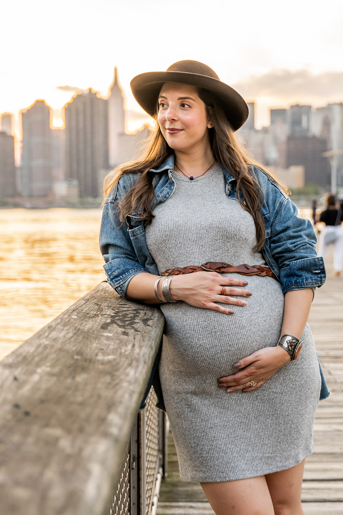 pregnant woman with hat on in queens with nyc skyline