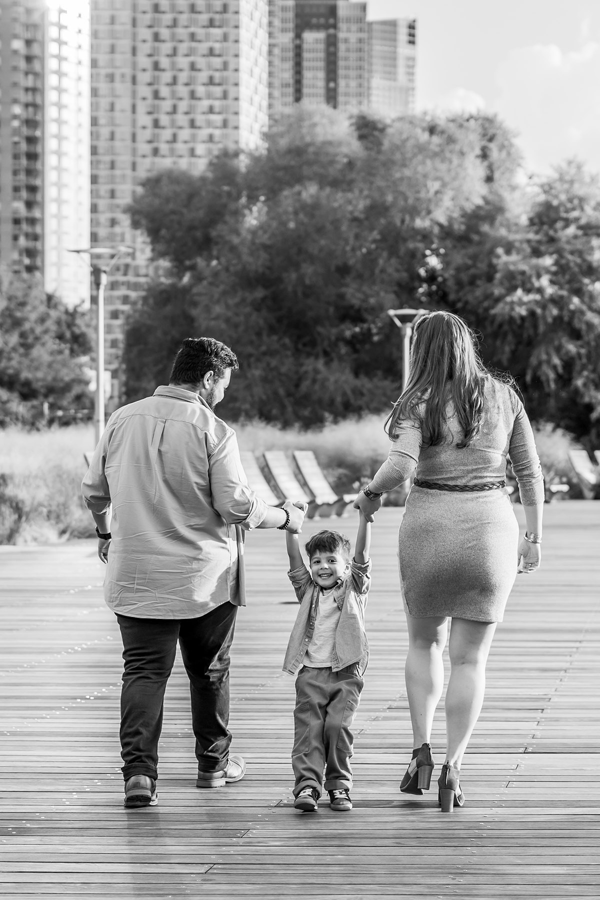 BW photo of parents walking through hoboken holding their son's hands