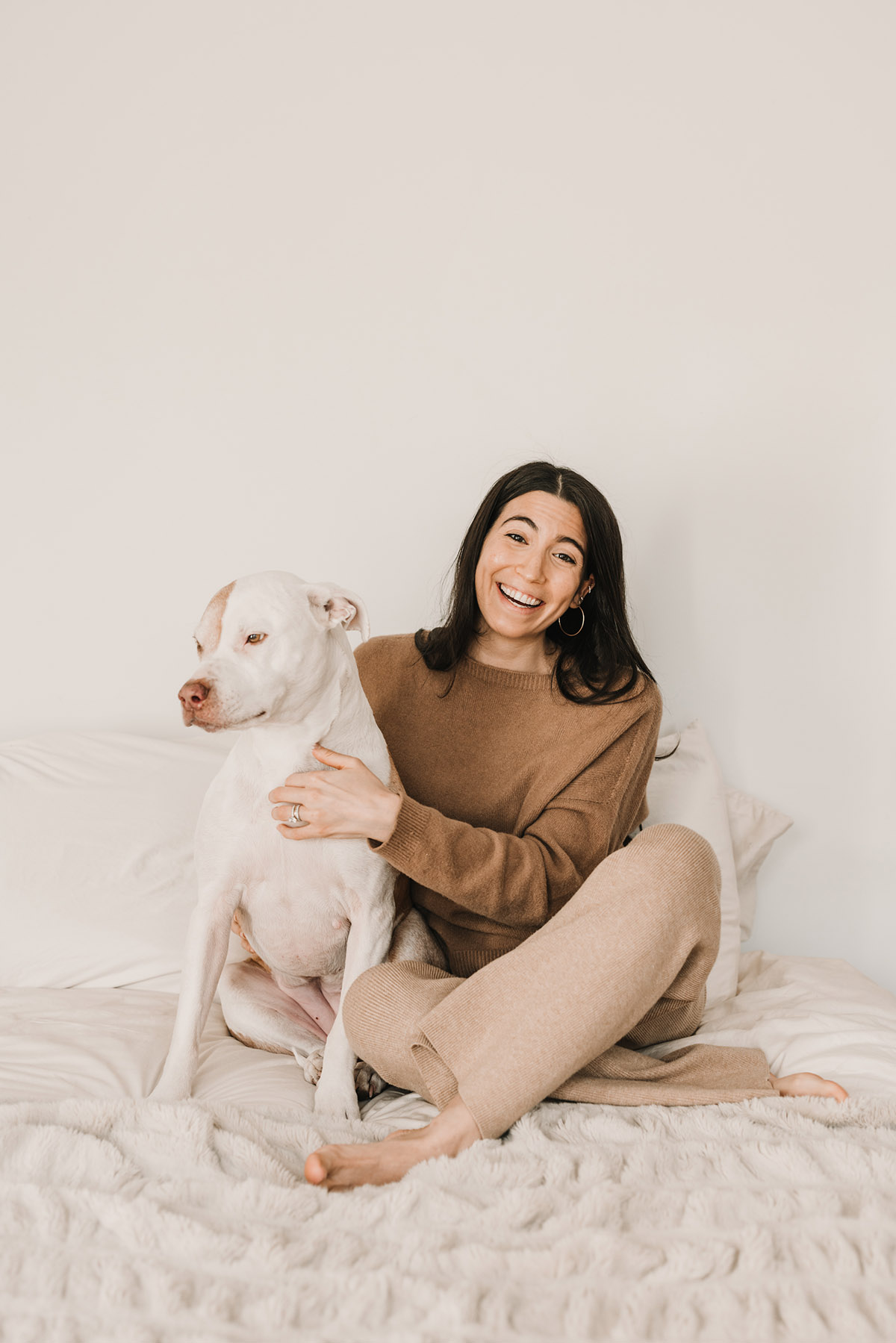 laughing woman with dog sitting on bed