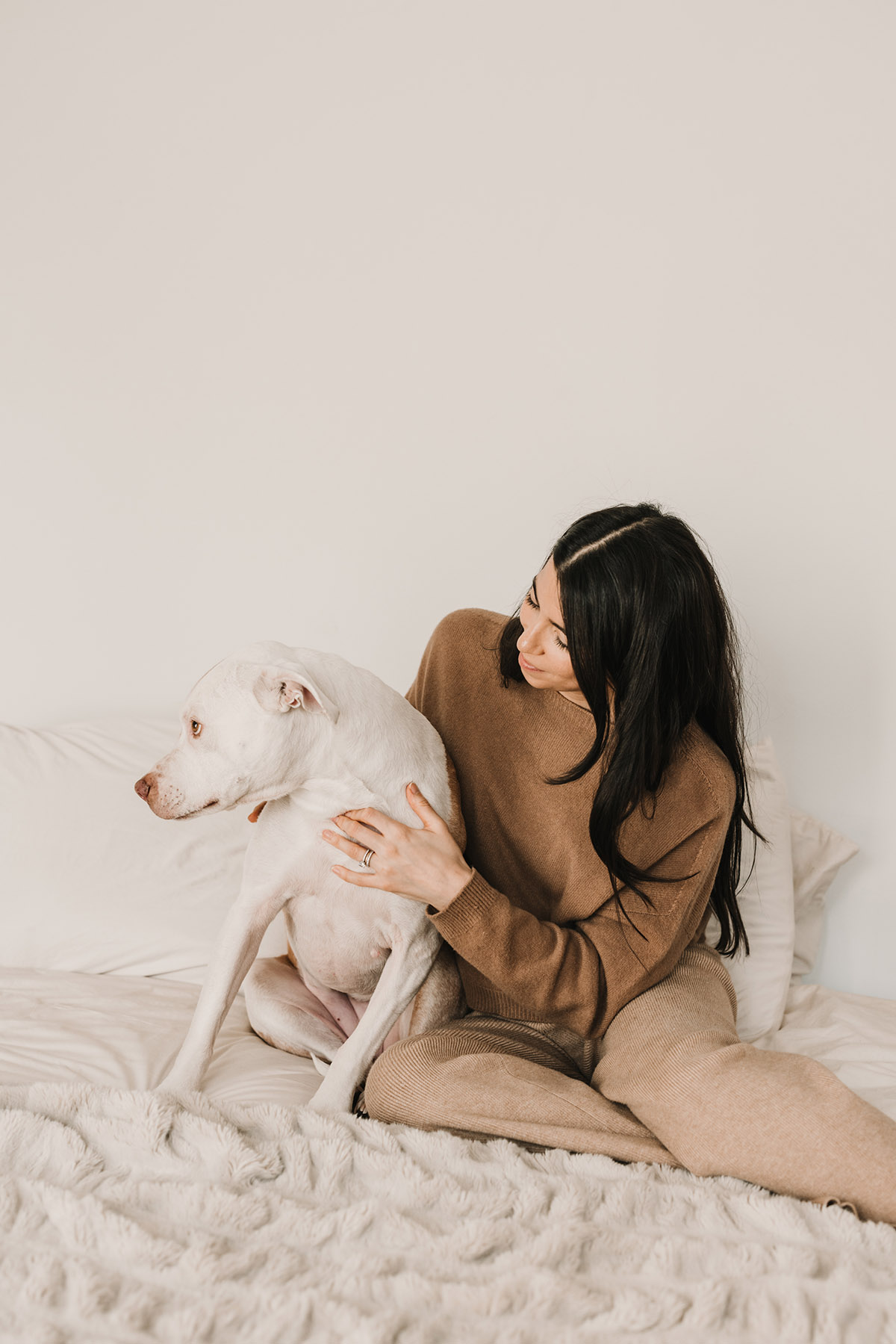 woman with dog sitting on bed