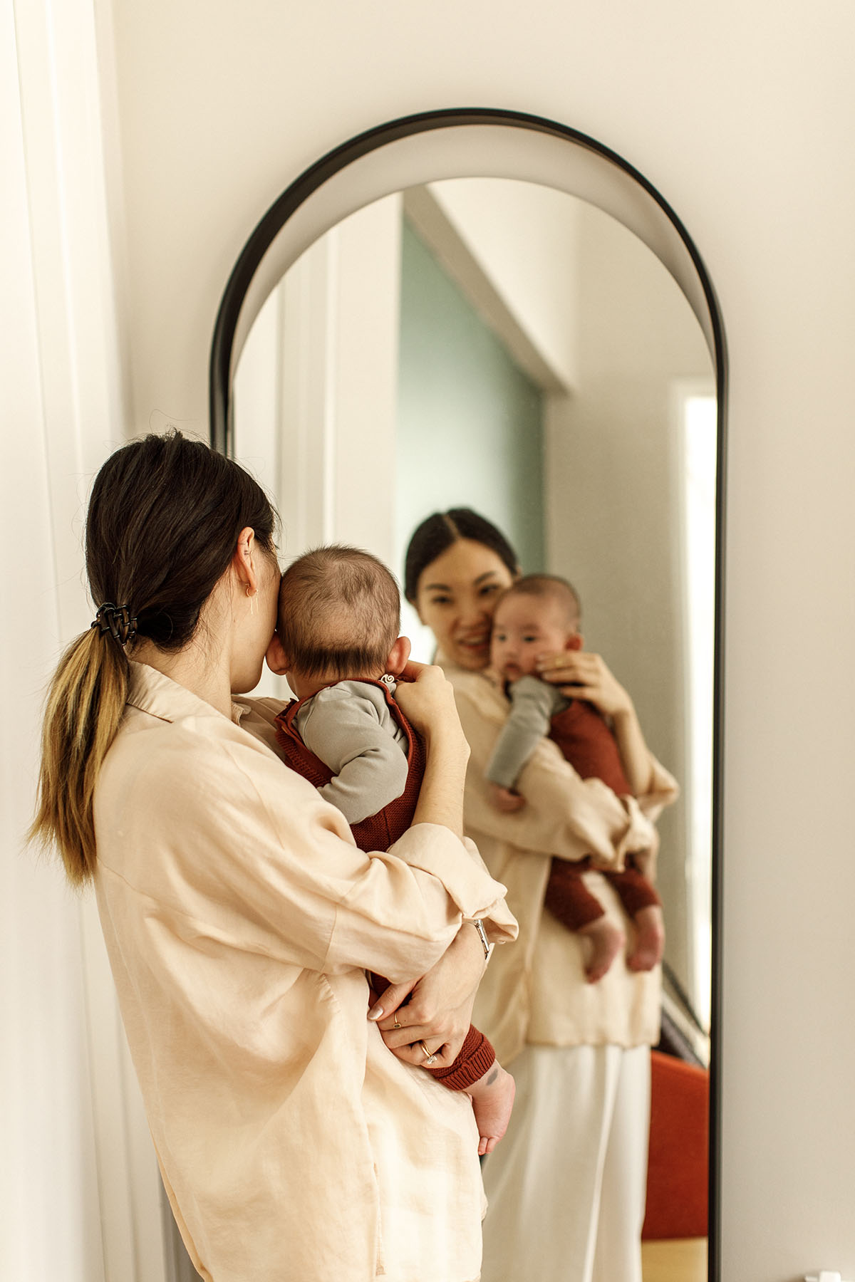 mom is holding newborn in front of a mirror