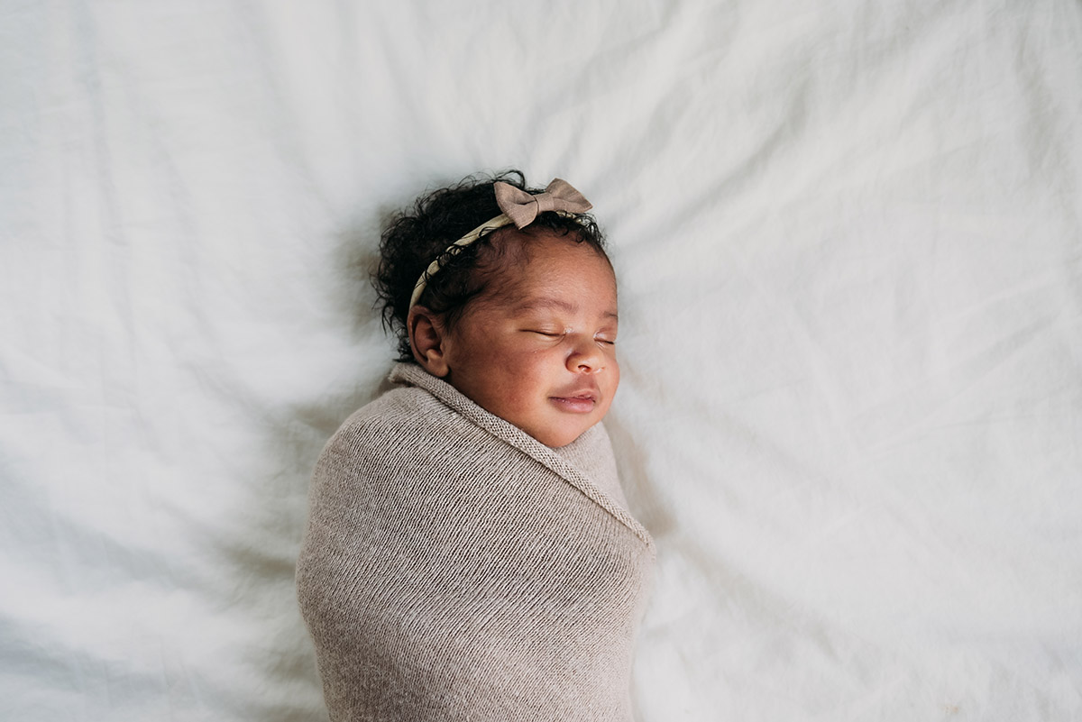 smiling and sleeping newborn laying in bed