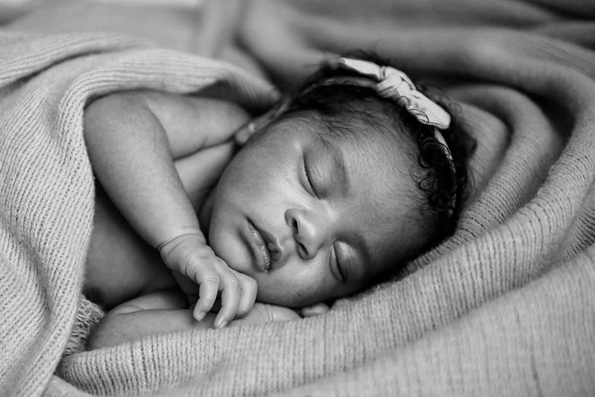 BW portrait of sleeping newborn with bow in her hair