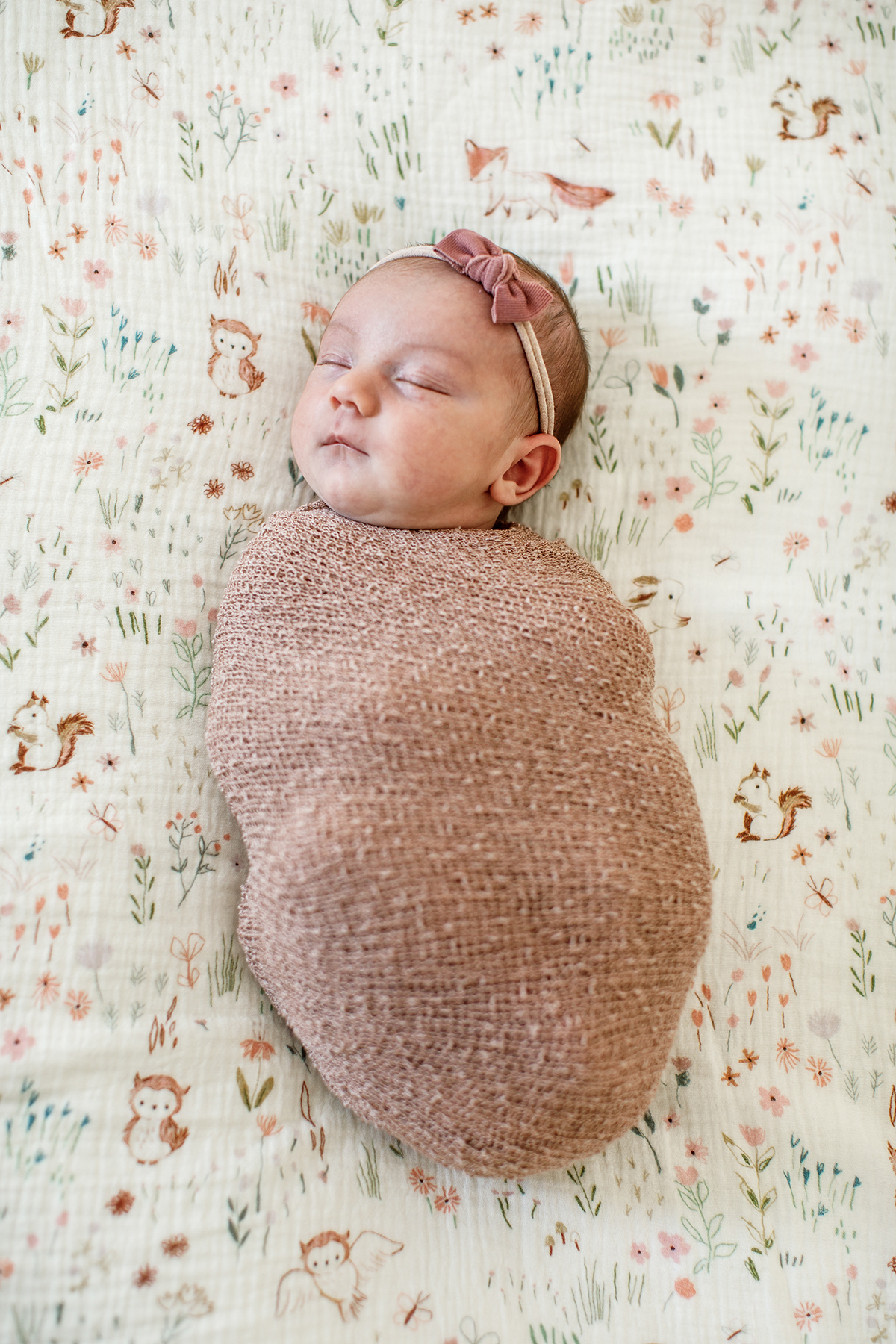 swaddled newborn baby girl with headband