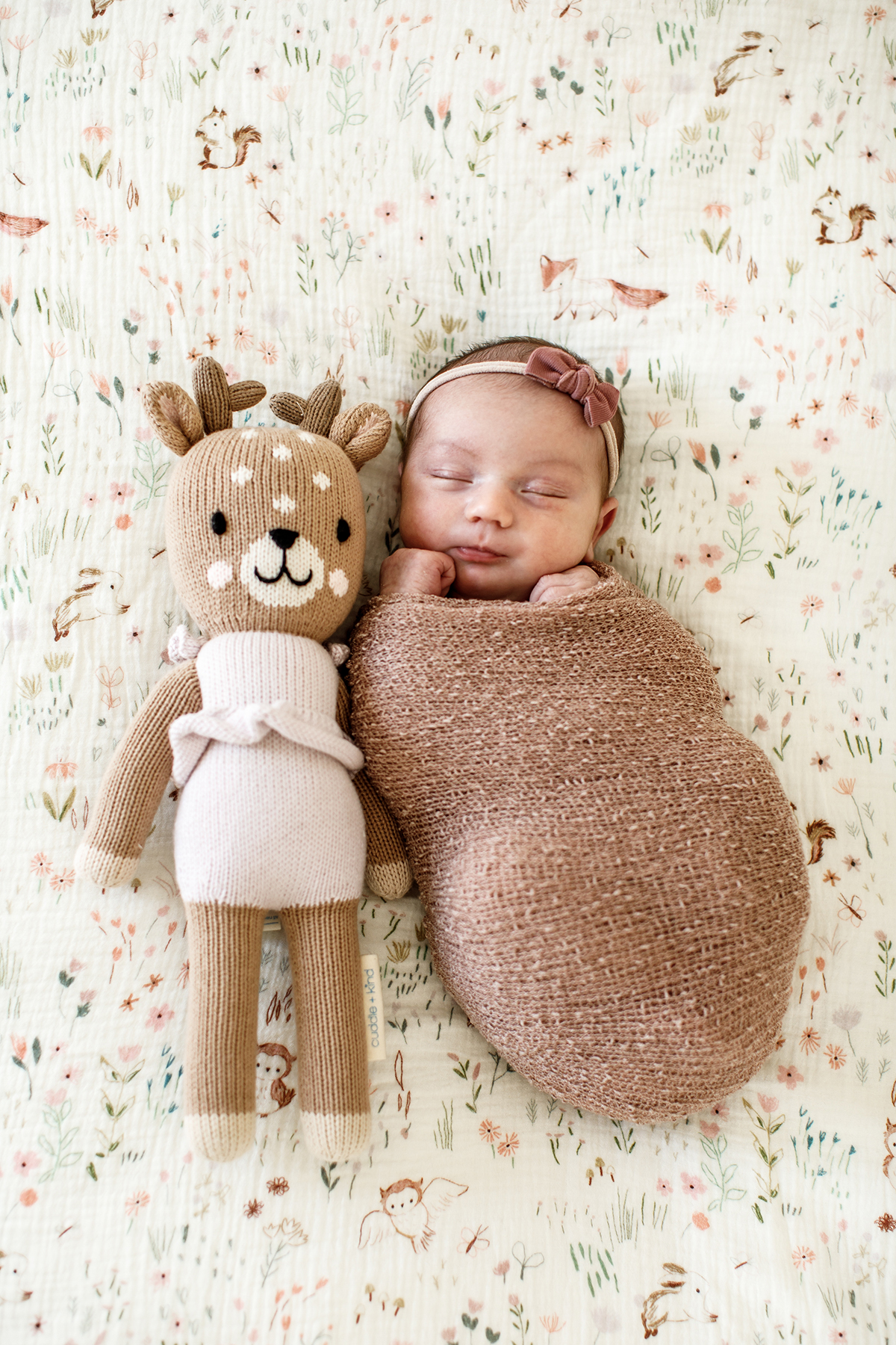 newborn baby girl sleeping with her stuff animal deer next to her