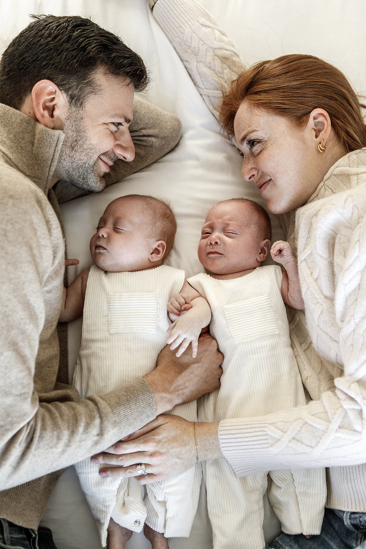 portrait of family laying in bed newborns between mom and dad