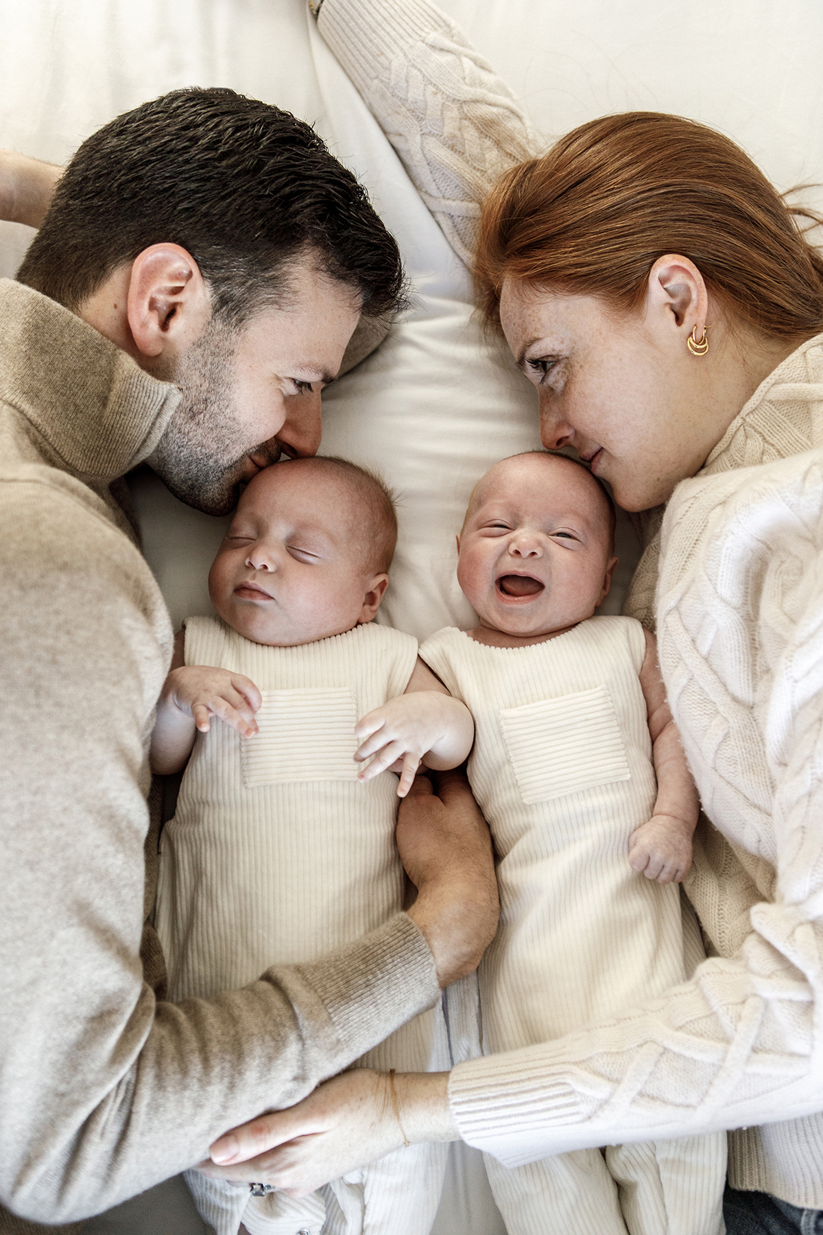 family of four laying in bed twin babies between mom and dad