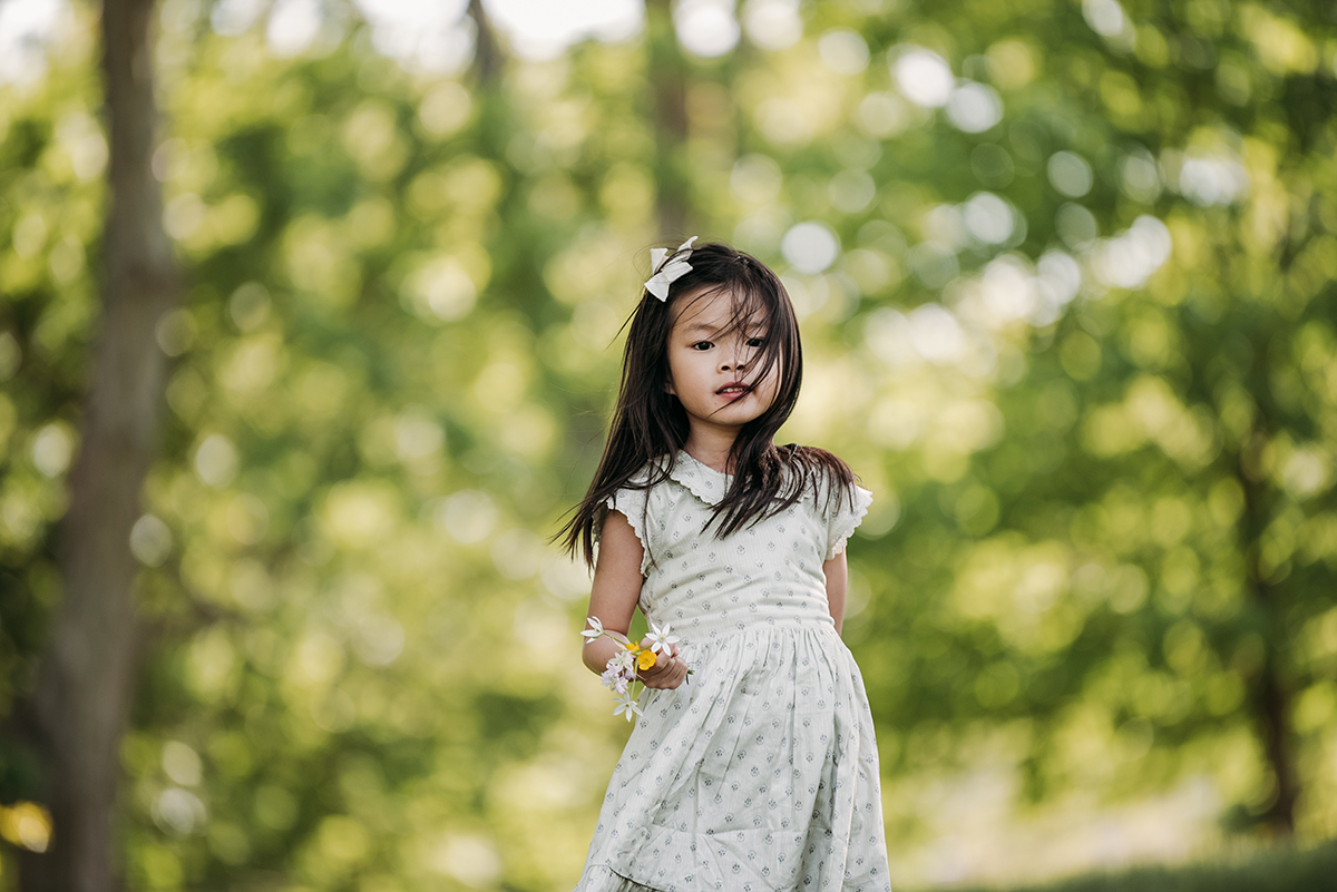 little girl in a dress bow in her hair holding flowers in her hand