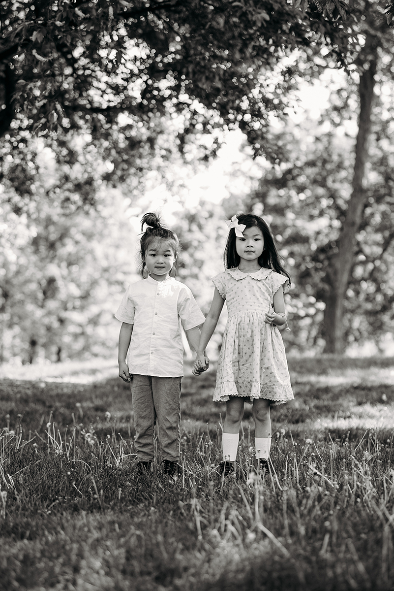 black and white photo siblings standing in a park holding hands