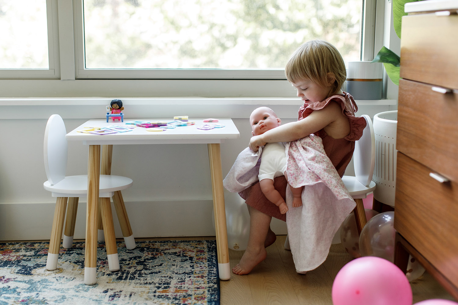 little girl tending to her baby doll in nursery