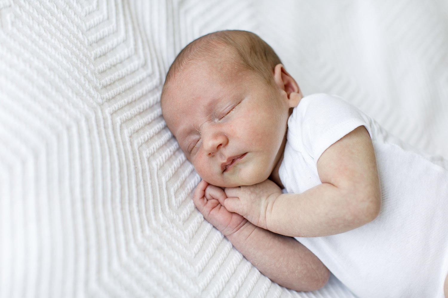 sleeping newborn baby in white onesie