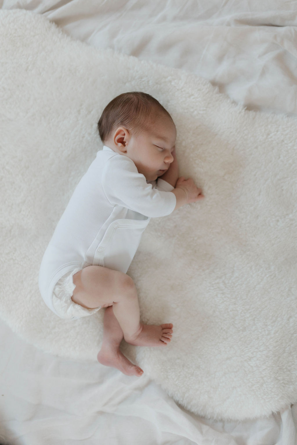 newborn sleeping on white furr