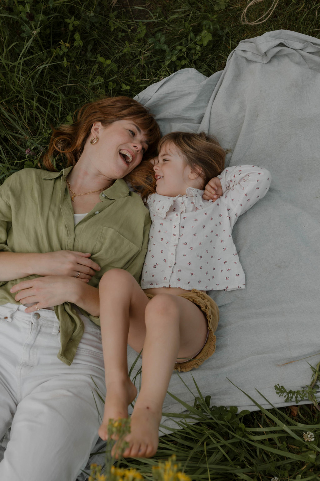 mom and daughter cuddling outside on picnic blanket