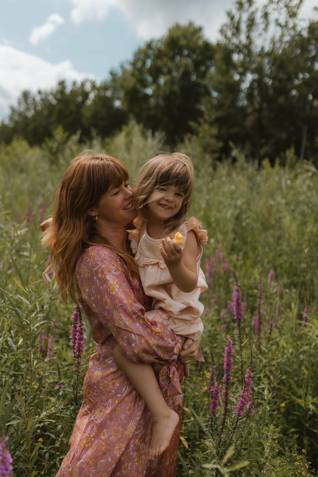 mom holding her daughter in a field of grass