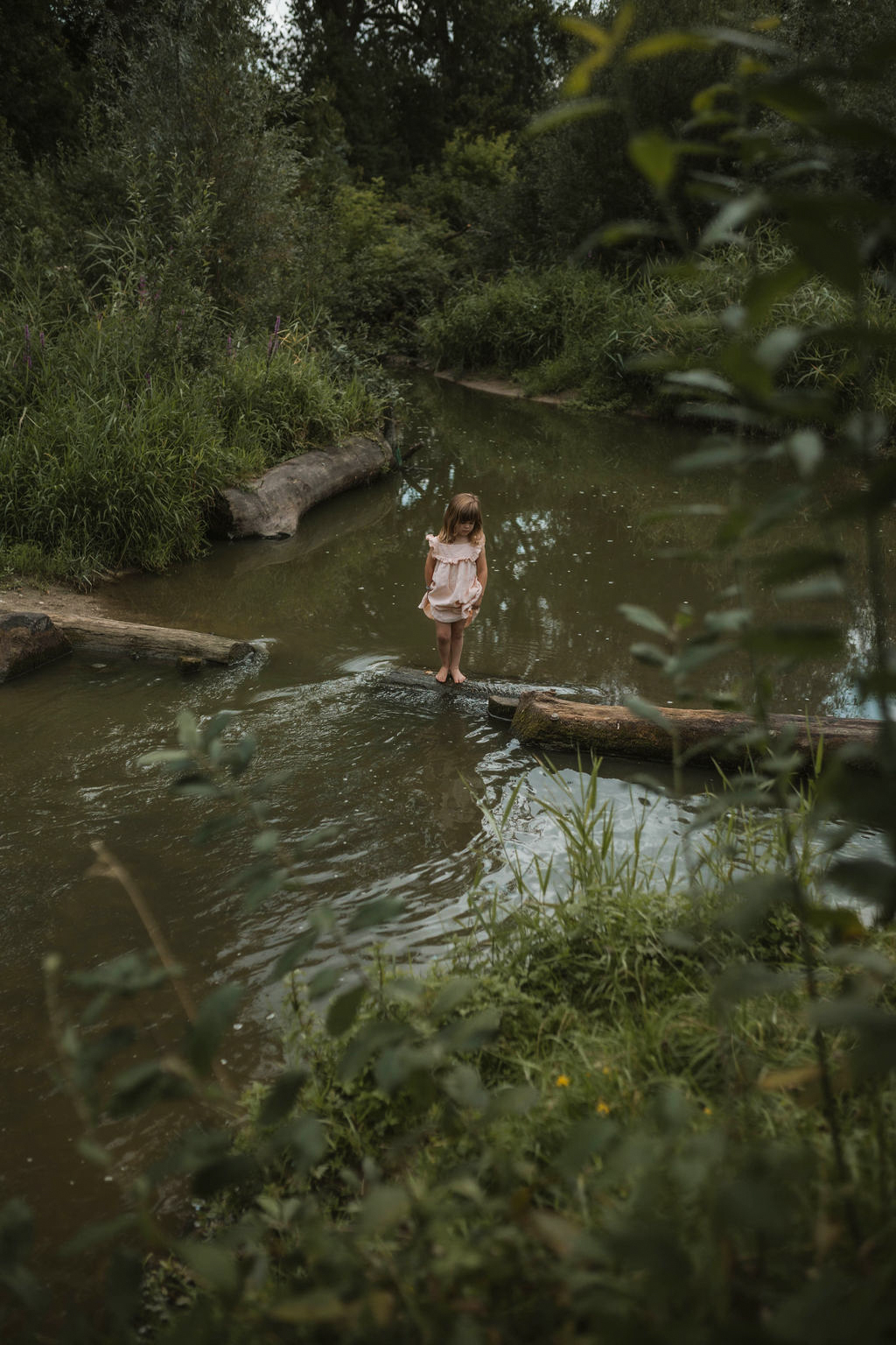 girl balancing on tree floating in the river