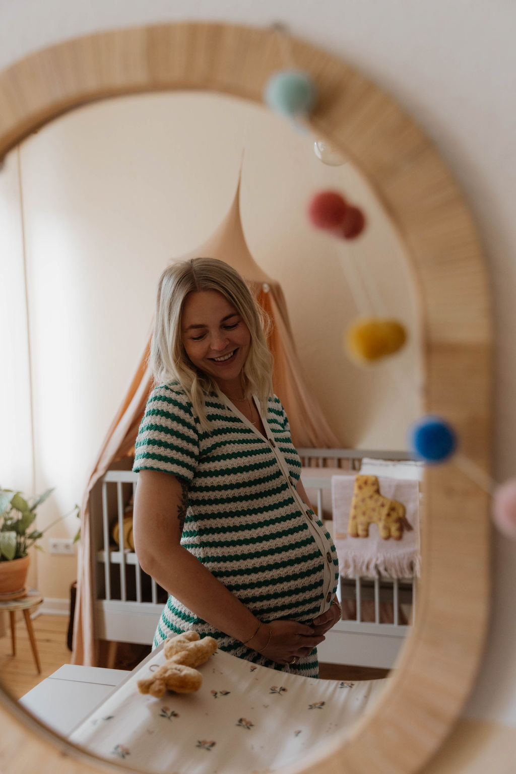 pregnant woman photographed smiling in nursery mirror