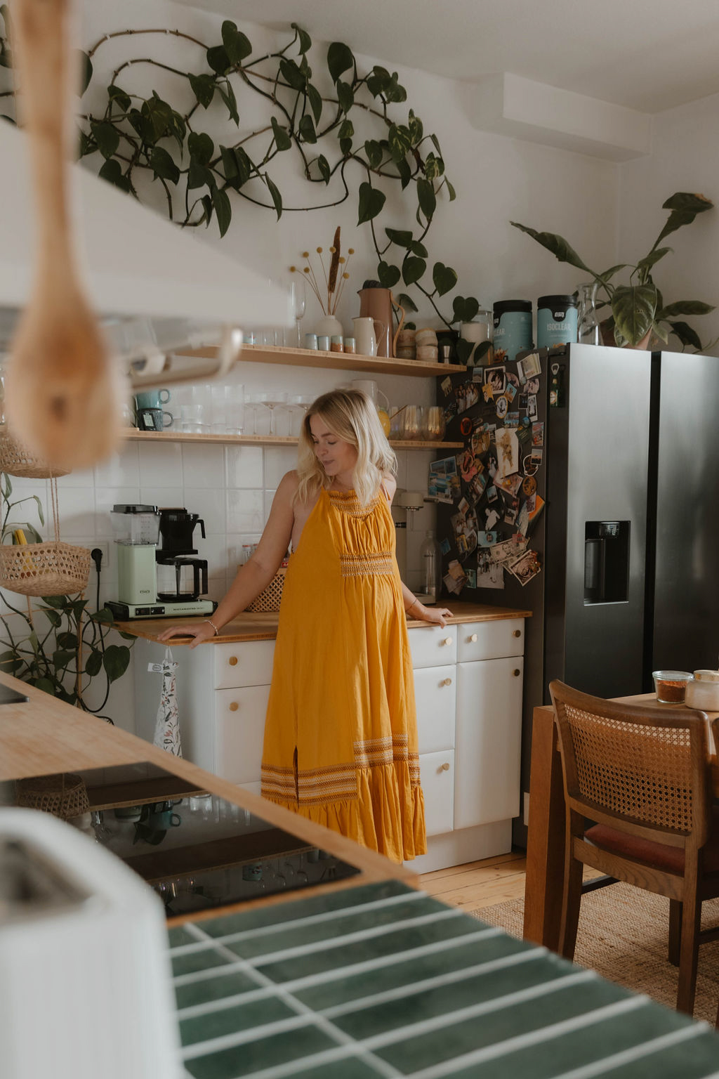 pregnant woman in a long yellow dress leaning against a counter in a kitchen
