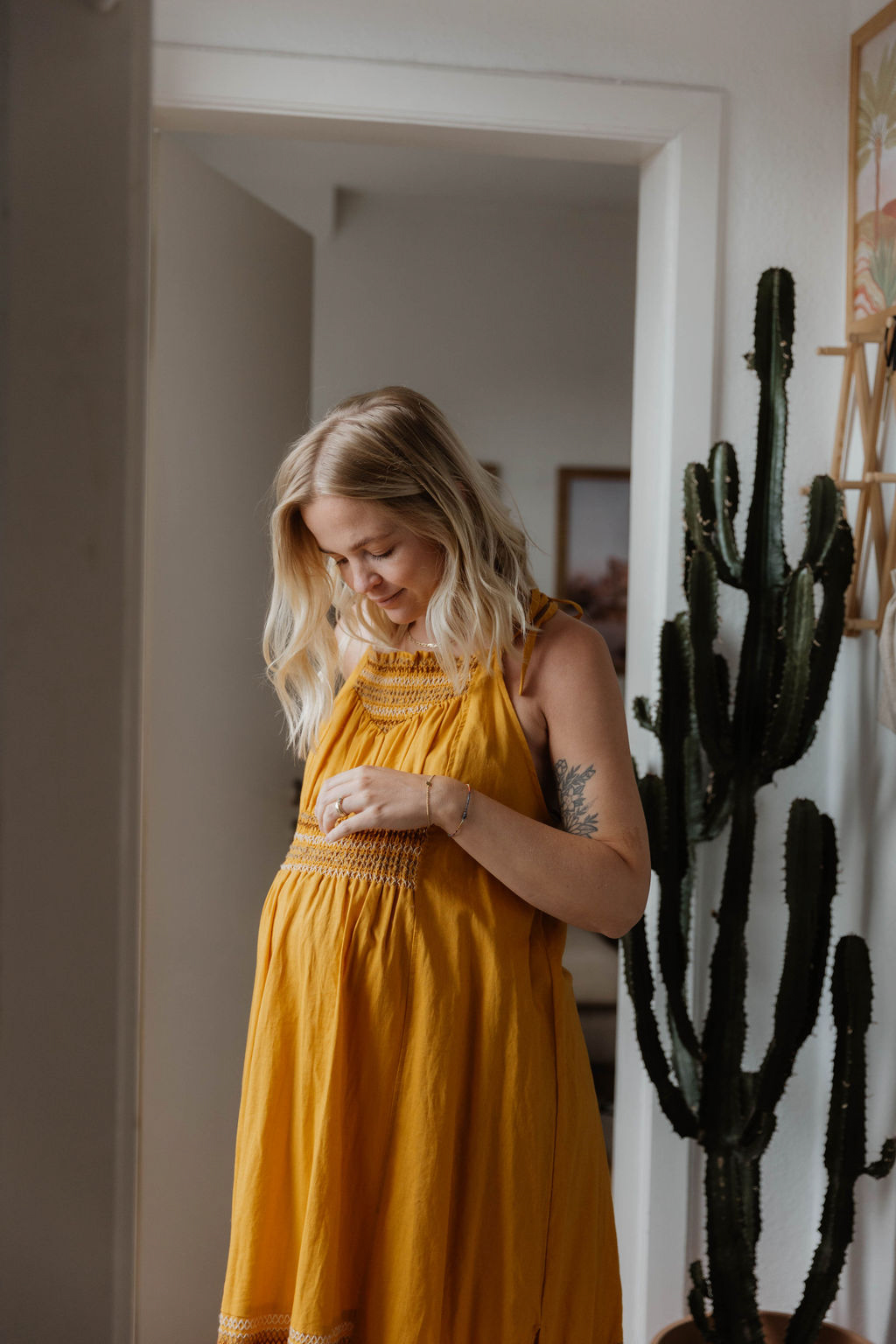 pregnant woman in a long yellow dress looking down