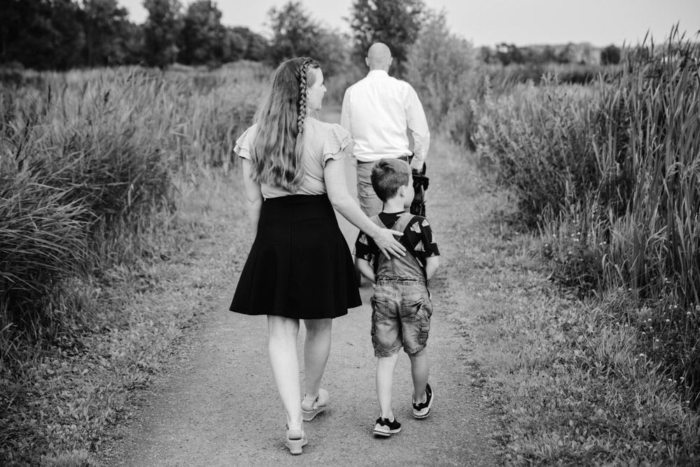 family of three walking by some fields away from the camera