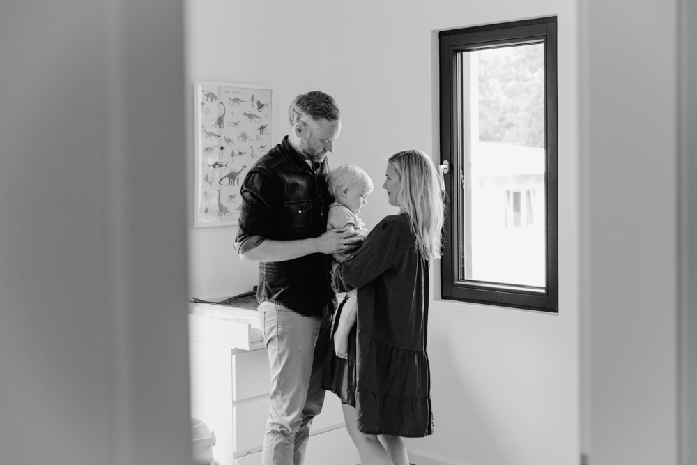 black and white photo parents holding their baby in the nursery