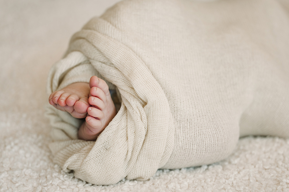 close up of a baby's feet sticking out of a blanket