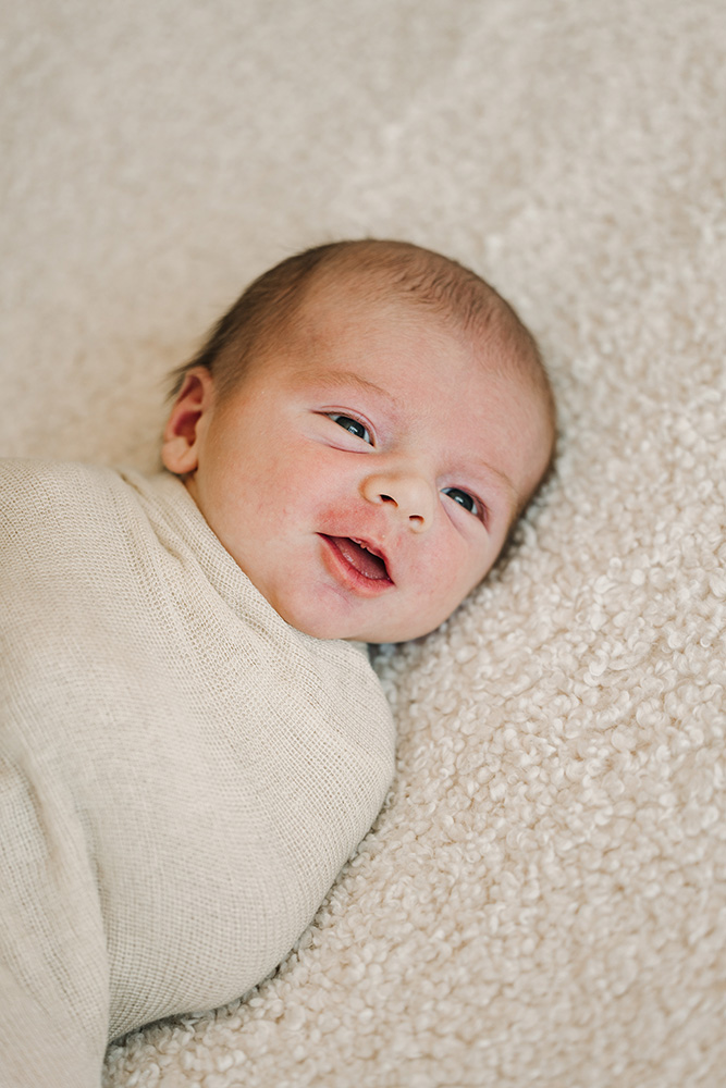 close up of a baby cuddle up in a blanket smiling