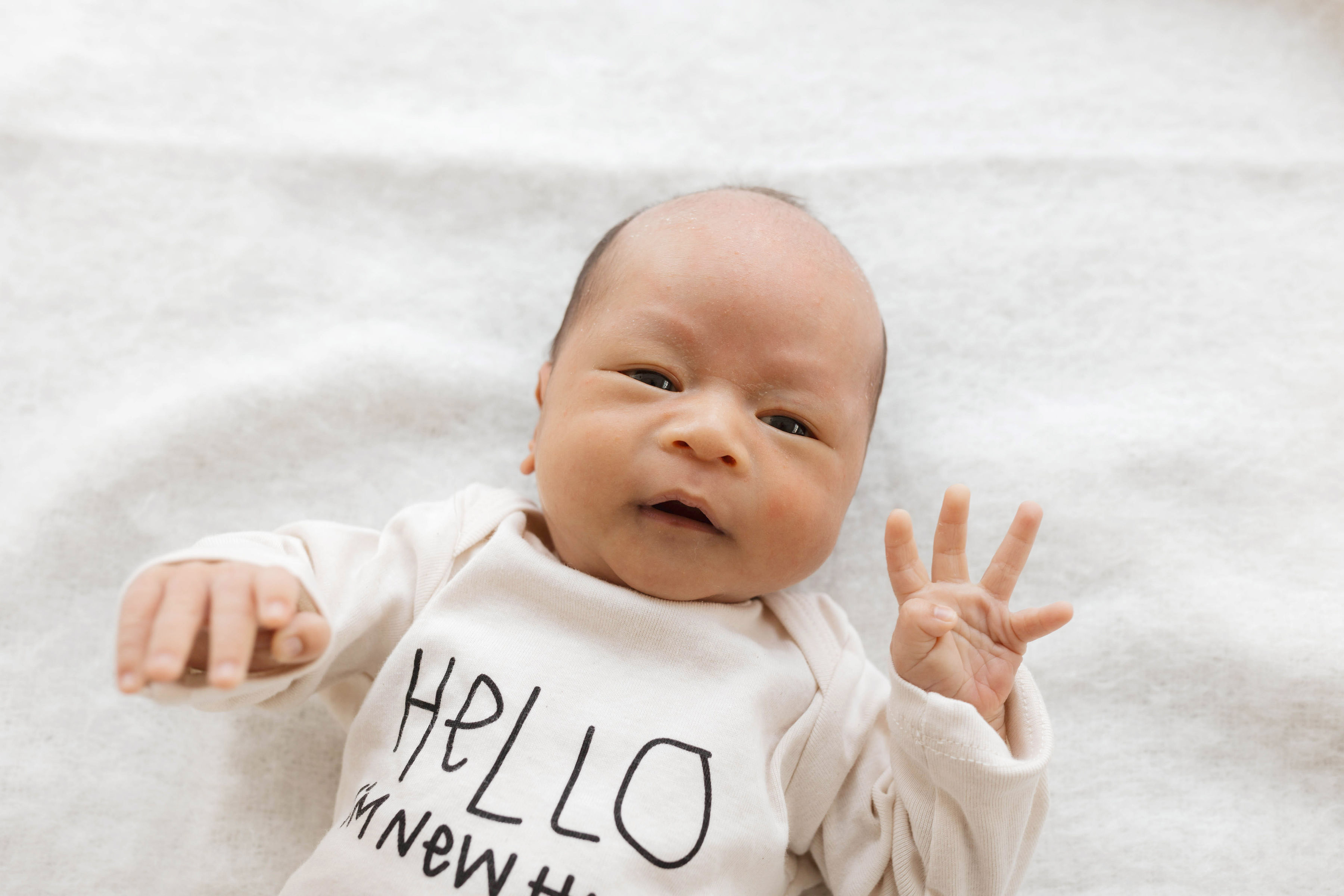 close up of a baby wearing a romper that says "Hello I'm new here"