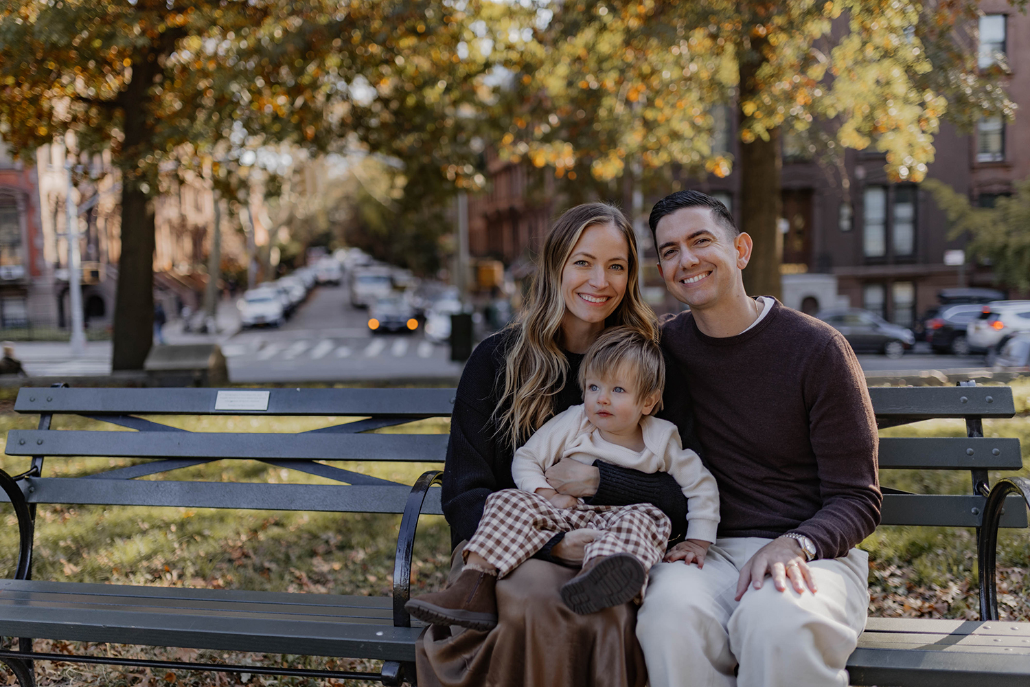 Family of three sitting on a bench in Brooklyn in a Fall Season mood