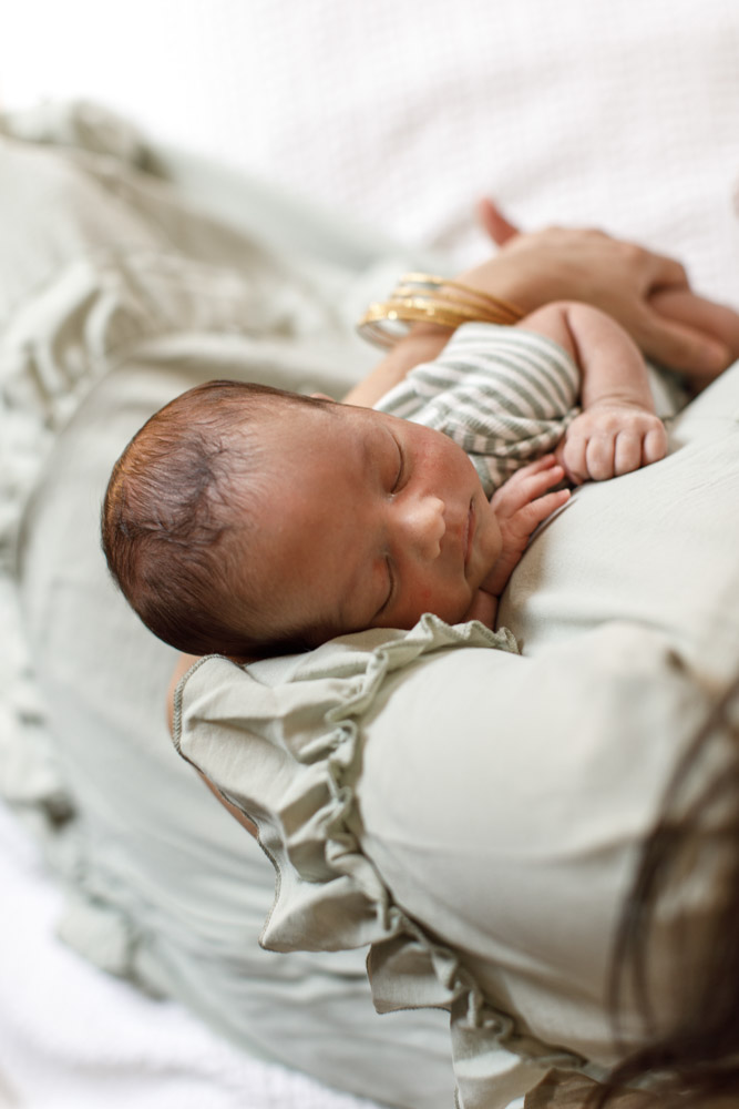 close up of sleeping newborn lying in mother's arms