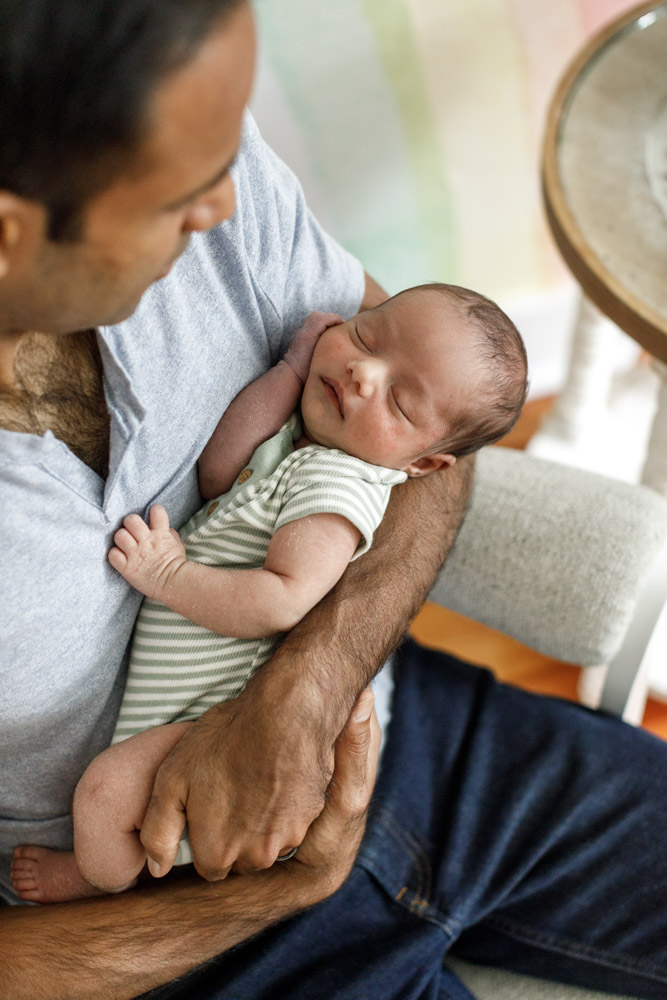 father is holding his sleeping newborn in his arms