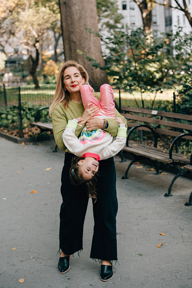 mother is holding her daughter upside down in Madison Square Park New York
