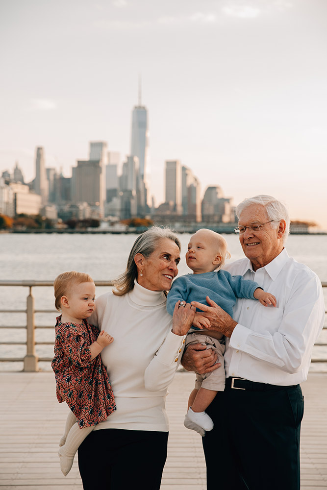 gransparents are holding their two grandchildren with Manhattan backdrop