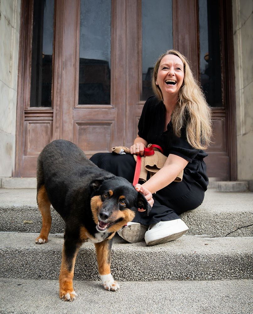 woman with black dog sitting on stairs laughing