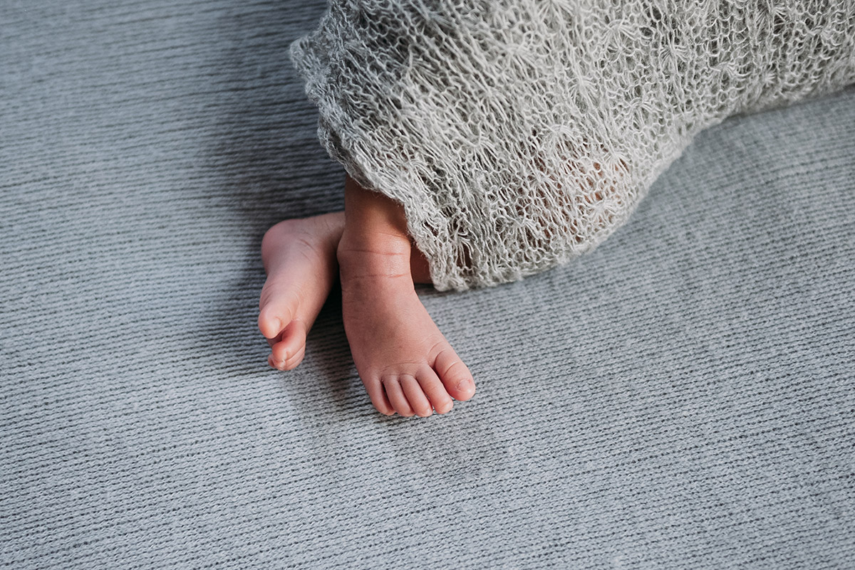 close up of baby´s feet while newborn is swaddled in a white blanket