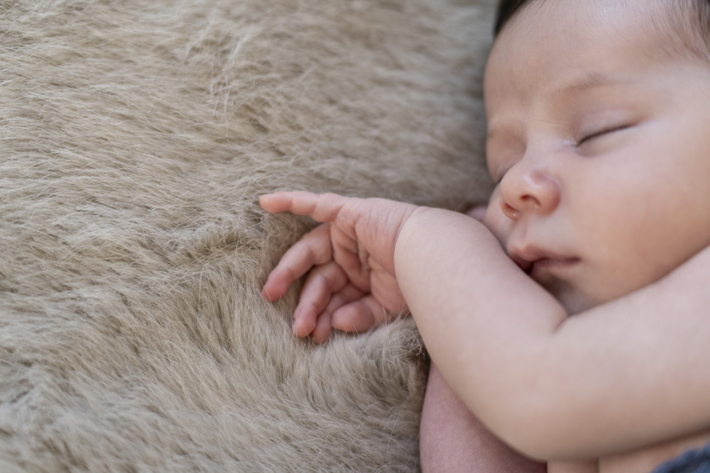 close up of sleeping newborn lying on a beige blanket
