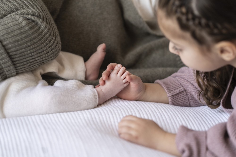 close up of toddler holding newborn's foot