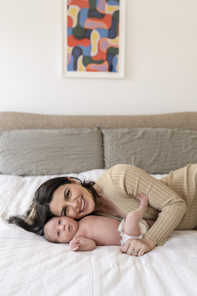 mother and newborn lying on the bed smiling at the camera