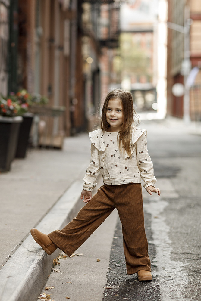 little girl standing on the street with one foot on the curb smiling