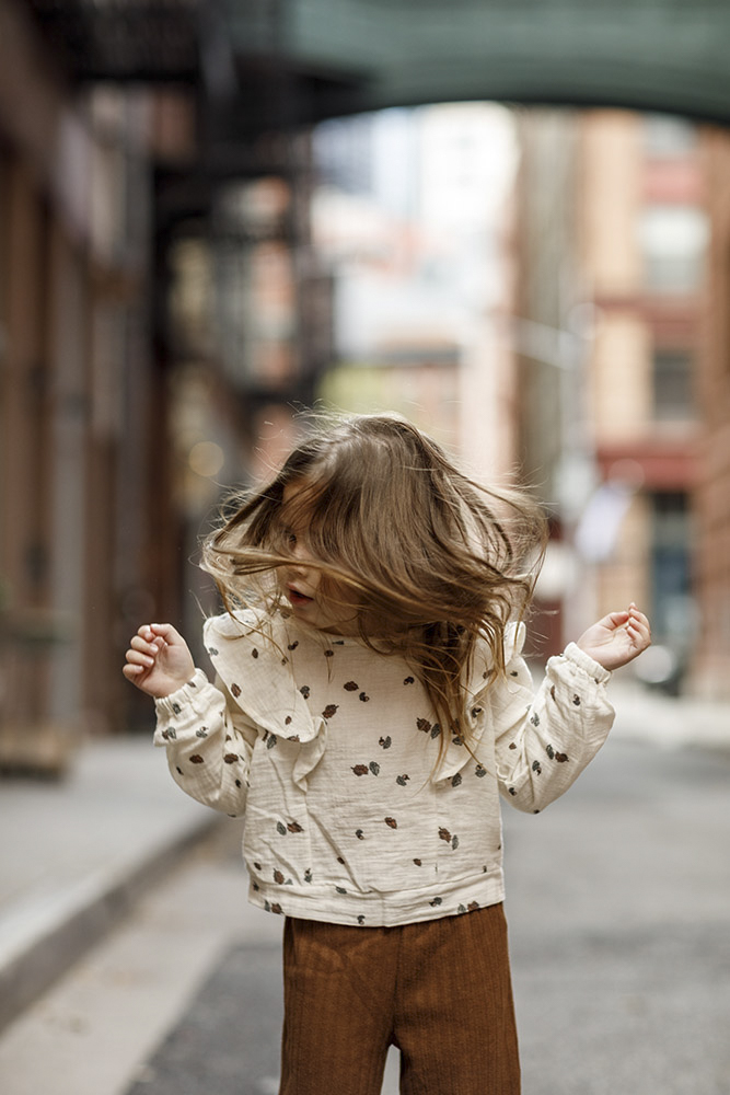 close up of toddler jumping and shaking her head with hair flying in the streets of New York