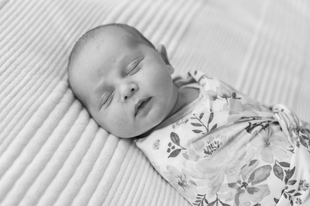 black and white photo of a sleeping newborn wrapped up in a blanket