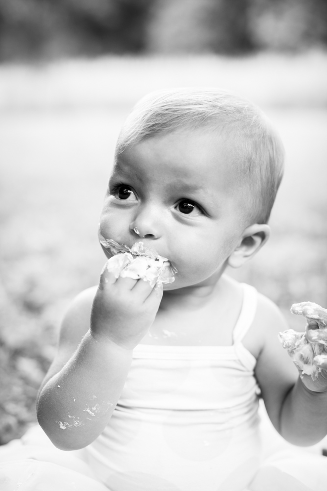 black and white photo of a toddler eating cake with her hands