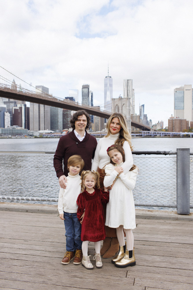 Family Session, family of five are standing on a pier, the background is the Brooklyn Bridge