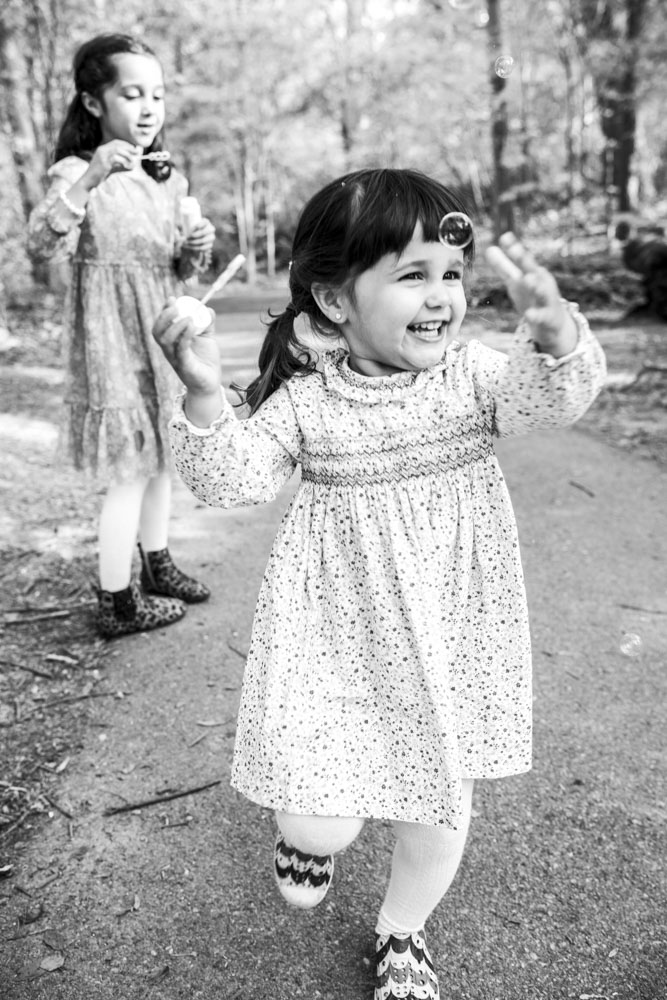 Family Photography, black and white photo of two girls in pretty dresses chasing bubbles