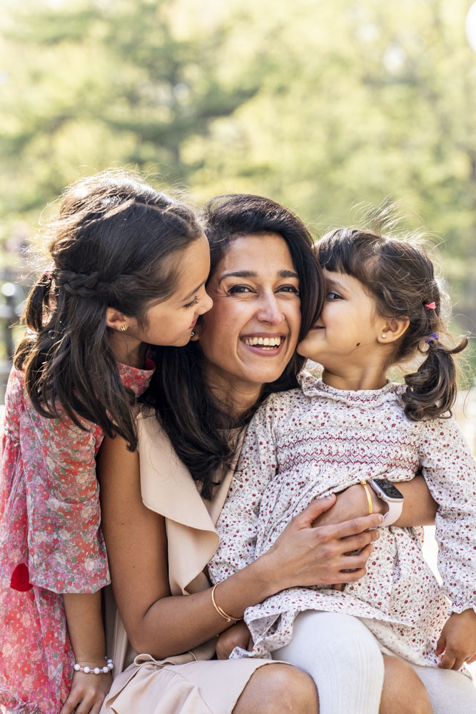 Family Photography, photo of mother with her two little daughters in a park, both girls are kissing mothers cheek