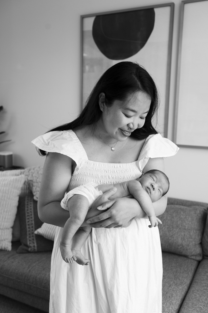 Baby Session, black and white photo of mother in a white dress holding her newborn baby in her arms