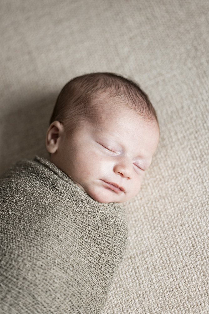 Baby Photography, close up of a sleeping newborn swaddled in a green blanket