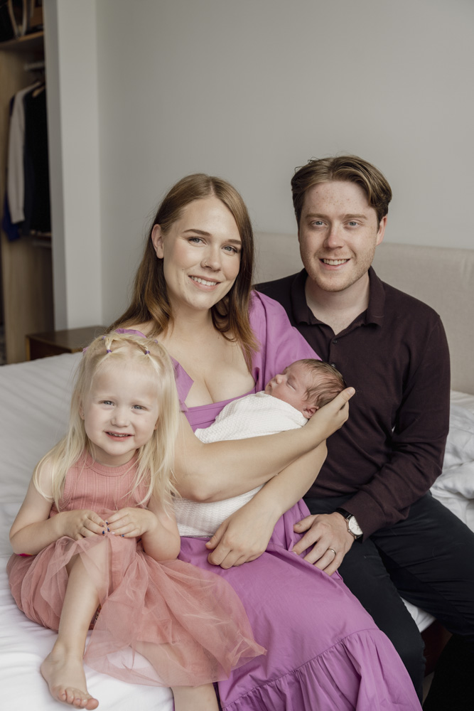 Family Photography, family of four sitting on the bed while mother is holding the newborn baby