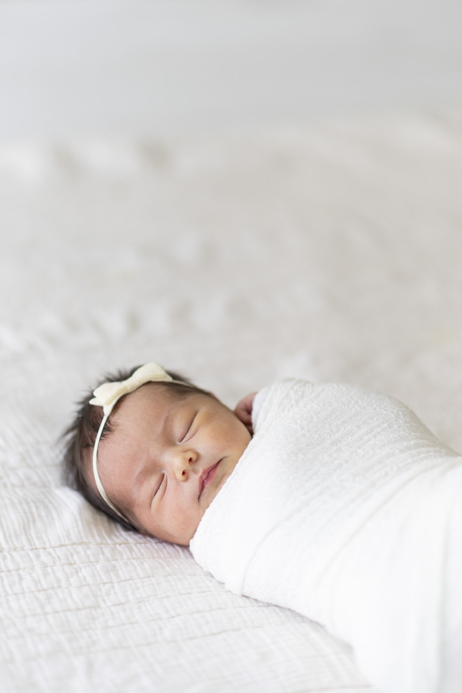 Baby Session, newborn wearing a bow eyes closed swaddled in a white blanket